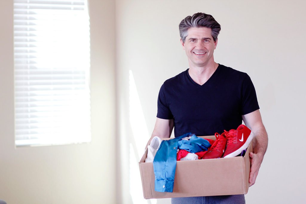 Joshua Becker, from Becoming Minimalist, smiling and holding a box, ready to teach readers how to declutter